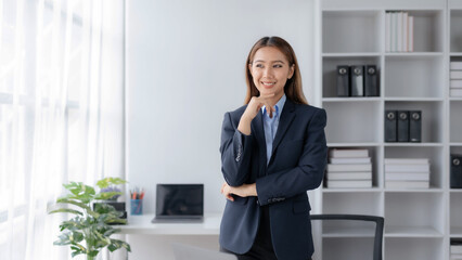 Confident Asian Businesswoman Standing in Office, Looking at Camera with Professional Demeanor. Modern Asian Business Professional.