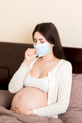 Pregnant woman in protection mask sitting on sofa. COVID-19 Coronavirus. Prevent infection to the fetus