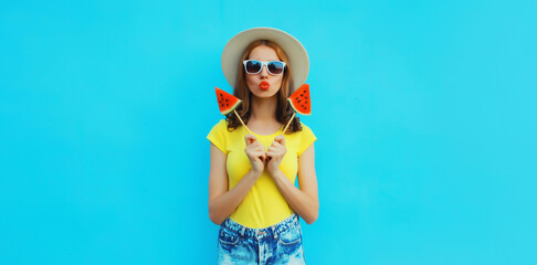 Summer portrait of young woman with sweet juicy lollipop or ice cream shaped slice of watermelon wearing straw hat on blue background