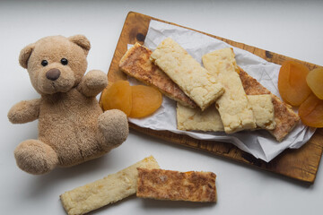 Healthy homemade sugar free grain cookies with dried apricots on white paper with baby toy bear, selective focus