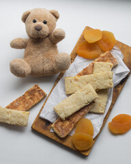 Healthy homemade sugar free grain cookies with dried apricots on white paper with baby toy bear, selective focus