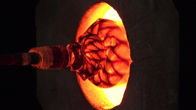 Glassblowing and glass being shaped in a hot furnace