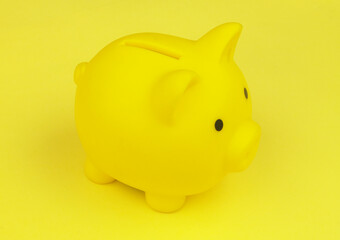 Yellow piggy bank on yellow background. Saving money concept.