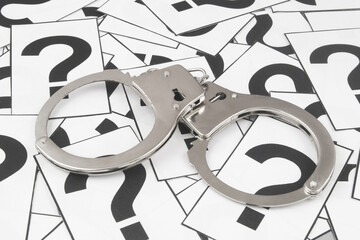 Steel handcuffs on question marks background. Concept of justice and crimes FAQ. 