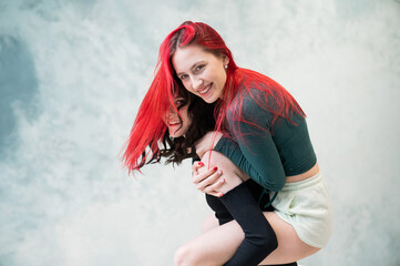 Two friends are fooling around. Young caucasian woman on the back of another. 