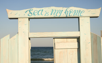 Sea is my home. Concept photo with a white wood door placed on a beach at the seaside. Beautiful summer image.