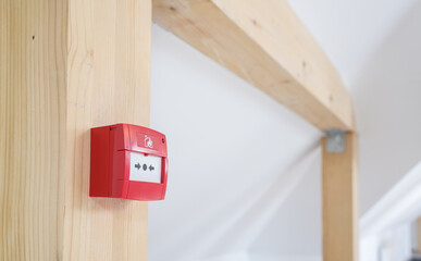 Obraz na płótnie Canvas Emergency fire alarm button on a wooden pole inside the attic of a house. Emergency alert devices.