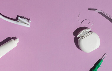 Dental care concept composition with toothbrush, tooth floss and toothpaste on the bright violet background. Copy space