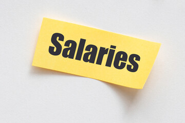 SALARIES Concept. The word SALARIES on a small sheet in an office notebook.