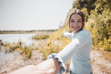 A young attractive woman taking her lover hand in hand leading to the lakeside during sunset by pov camera angle . High quality photo - obrazy, fototapety, plakaty