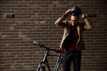 A smiling businessman putting the helmet on his head for a bicycle ride.
