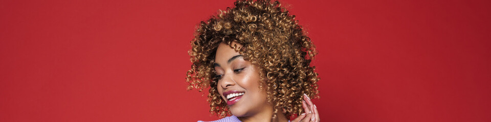 Fototapeta premium Young black woman with afro curls smiling and posing at camera