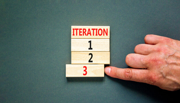 Time to iteration 3 symbol. Concept word Iteration 1 2 3 on wooden block. Businessman hand. Beautiful grey table grey background. Business planning and time to iteration 3 concept. Copy space.