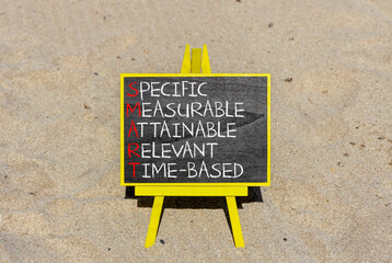 SMART symbol. Concept words SMART specific measurable attainable relevant time-based on blackboard. Beautiful sand background Business SMART specific measurable attainable relevant time-based concept