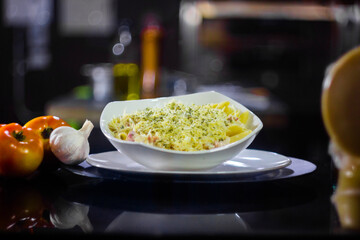 Special view with Italian food on dark background with pasta, tomatoes, garlic, pepper, cheese and kitchen background.