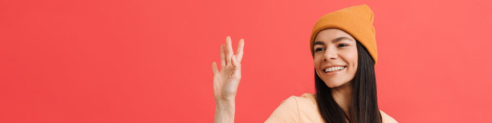 Young excited girl wearing hat waving and holding cellphone