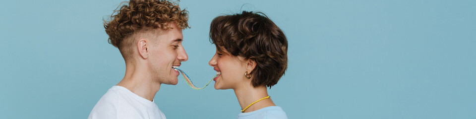 Young beautiful smiling couple eating rainbow candy together