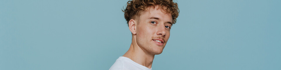 Obraz premium Young handsome curly man holding phone and looking at camera