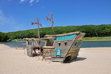 Children's pirate ship on the shore of the lake on a sunny summer day