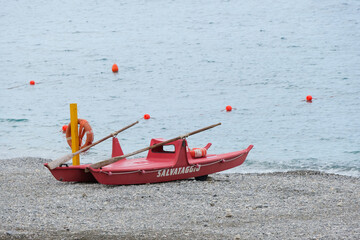 Un pattino di salvataggio rosso in riva al mare.
