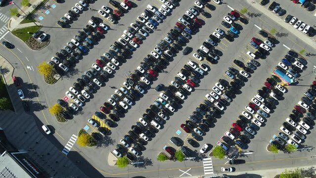 An aerial top overhead view of parking with many places near the supermarket. Cars moving around busy parking lot near shopping center. Drone footage of huge parking in Canada