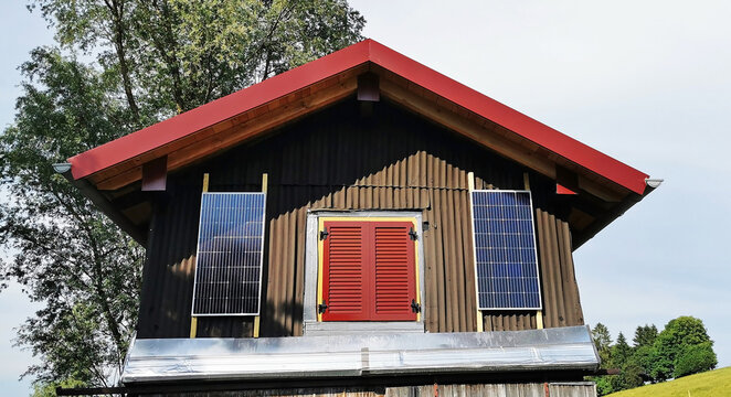Solarmodule zur Stromerzeugung an einem kleinen Holzhaus. Ein kleines Balkonkraftwerk an einer Hütte