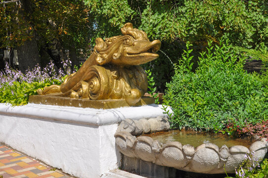 Old beautiful goldfish fountain in the city park on a sunny day