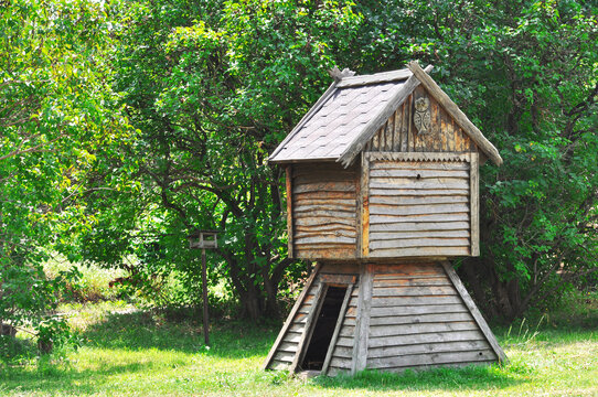 Children's fairy-tale wooden hut with a wooden owl on a sunny meadow against the background of green trees