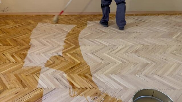 A worker is applying a scraper polish to a parquet that has deteriorated.