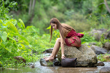 Beautiful Woman asia slim fitness model posing sexy in creeks wearing Sarong shower and wash a...