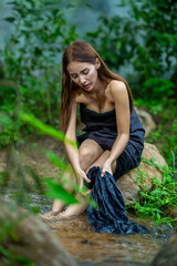  Beautiful women, cute, sitting, asia washing a clothes in the stream from the waterfall to show the lifestyle of people in the countryside with nature