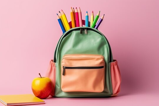 Bunter Schulrucksack mit Buntstiften, Apfel und Notizbuch vor pinkem Hintergrund, Schulstart, Generative AI
