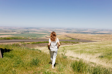 Naklejka na ściany i meble Beautiful summer landscape with meadows and a road from a bird's eye view. Nature in Oregon. A girl in sportswear with red hair walks in a summer meadow, rests in nature, admires nature