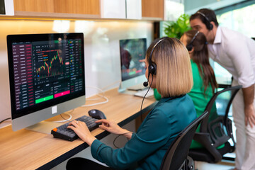 Back view. Stock trading center. Call center and one stop service. Attractive business Asian woman in suits and headsets working with desktop computer at telemarketing customer service agents