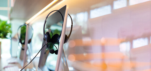VOIP headset on monitor of computer desktop at customer service and marketing support workplace. Office supplies of customer service. Communication support, call center and helpline concept.