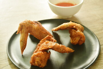 crispy fried chicken wing on black plate dipping with sweet chili sauce 