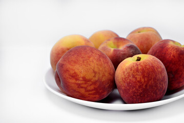 Juicy peaches on a white plate. Yellow-red large ripe peaches. Juicy fruits.