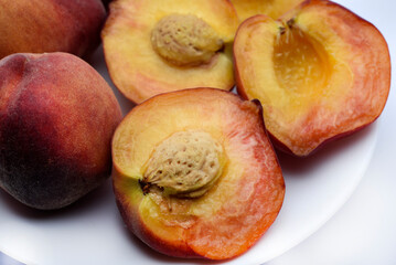 Naklejka na ściany i meble Juicy peaches on a white plate. Yellow-red large ripe peaches. Juicy fruits.