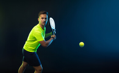 Padel tennis player with racket. Man athlete with paddle racket on court with neon colors. Sport concept. Download a high quality photo for the design of a sports app or betting site. - 617820896