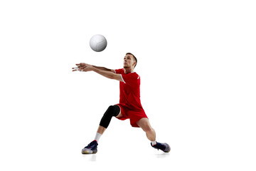Serving ball. Young concentrated man, professional volleyball player in red uniform in motion...