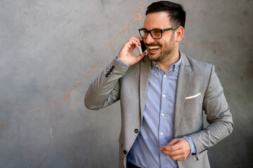 Portrait of successful businessman talking on smartphone in coffee break in office