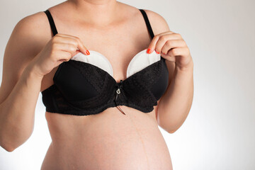 A girl in a black bra puts pads from the flow of milk in her bra. Soft, hypoallergenic breast pads.