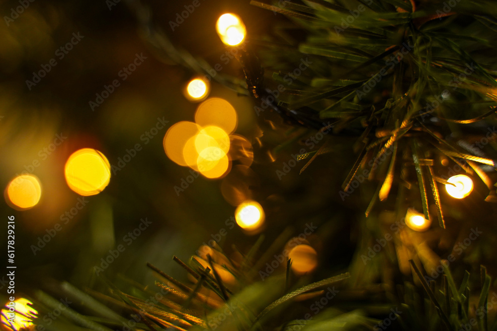 Poster artificial spruce branch with lights with bokeh effect. beautiful christmas tree against blurred lig