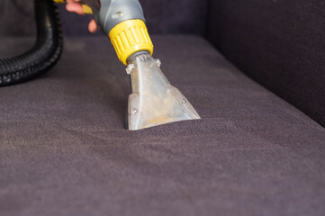 Dry cleaning of the black upholstery on the sofa with a special washing vacuum cleaner. Copy space...