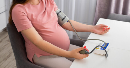 A pregnant girl measures blood pressure with a device. The concept of high and low blood pressure...