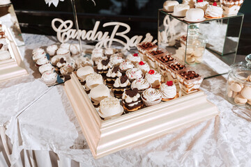 Festive dessert table with sweets. Wedding candy bar, various cakes, chocolates on stands.