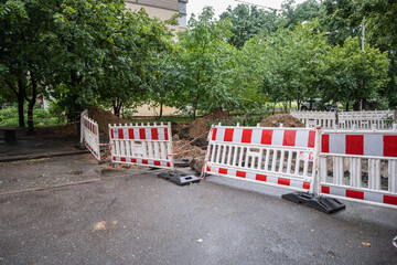 Fencing around an excavated trench in the yard of a residential area. Repair of sewerage, pipeline