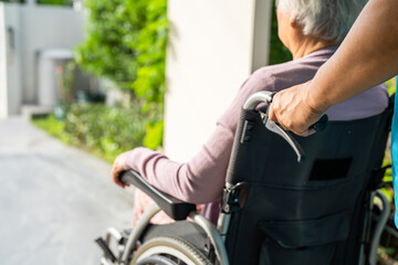 Obraz premium Caregiver help and care Asian senior woman patient sitting on wheelchair to ramp in nursing hospital, healthy strong medical concept.