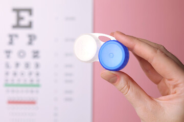 Contact lens container in hand on a colored background. Vision correction. 