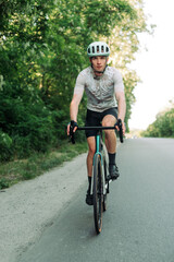 Photo of a male cyclist in gear riding on an asphalt road outside the city. Cycling as a hobby.